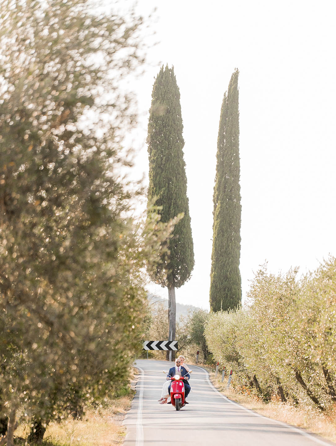 bride and groom riding a vespa in tuscany