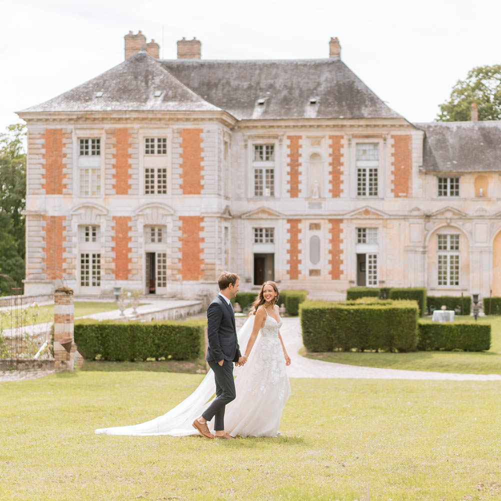 bride and groom walk hand in hand at chateau de vallery